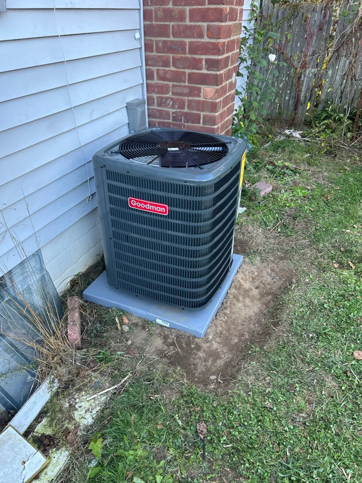 New Goodman condenser on a pad beside the house